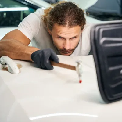 Technician smoothing dents on a car door